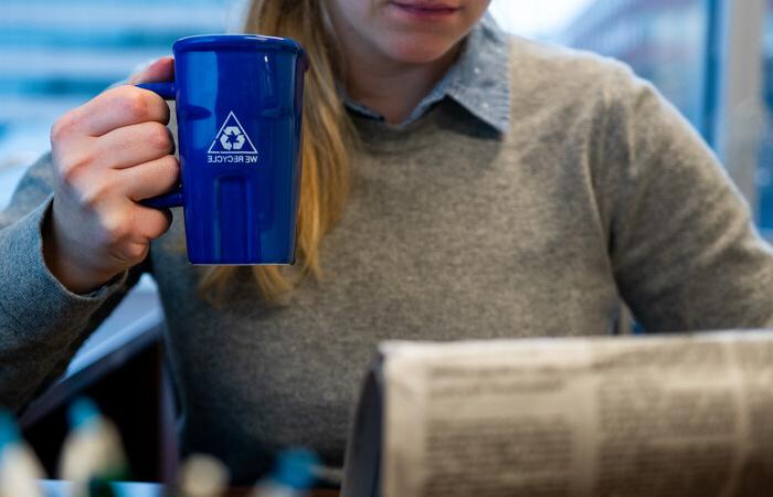 A person holding a mug that says we recycle